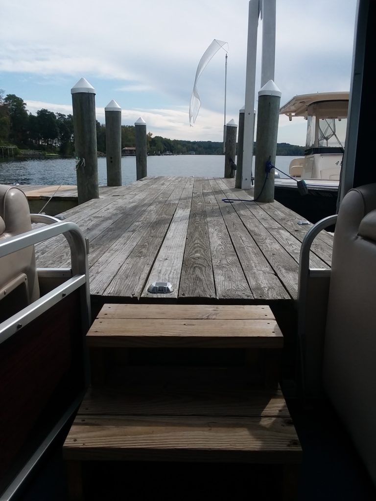 A view of a wooden dock from the interior of a pontoon boat. - Bianconi Tours